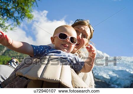 Low angle view of baby girl in sling sticking tongue out at camera View Large Photo Image Stock Photo - Low angle view of baby girl in sling sticking tongue out at camera. Fotosearch