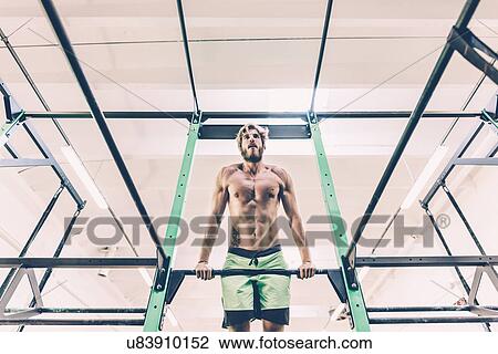 Low angle view of young male cross trainer training on exercise bar in gym View Large Photo Image Stock Image - Low angle view of young male cross trainer training on exercise bar in gym. Fotosearch