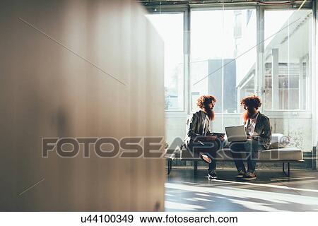 Male adult hipster twins sitting whilst working on laptop in office View Large Photo Image Stock Photo - Male adult hipster twins sitting whilst working on laptop in office. Fotosearch