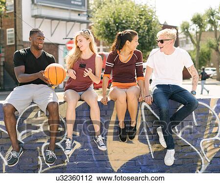 Male and female basketball friends sitting chatting in city skatepark View Large Photo Image Stock Image - Male and female basketball friends sitting chatting in city skatepark. Fotosearch