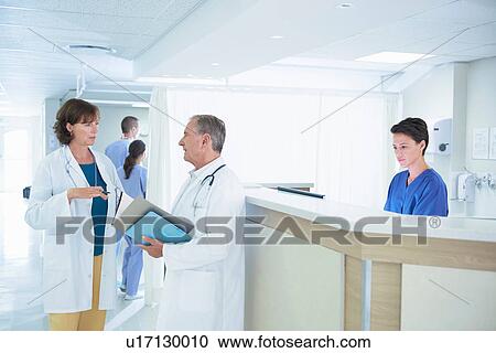Male and female doctors discussing medical notes at hospital nurses station View Large Photo Image Stock Image - Male and female doctors discussing medical notes at hospital nurses station. Fotosearch