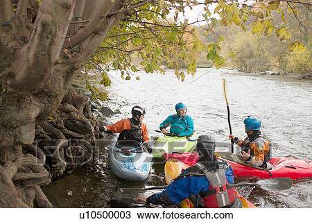 Stock Image - Male and female kayakers having team talk on River Dee, Llangollen, North Wales. Fotosearch