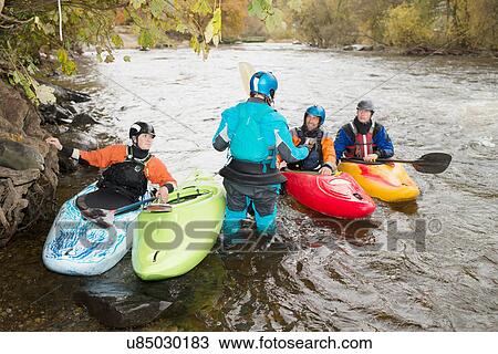Stock Image - Male and female kayakers having team talk on River Dee, Llangollen, North Wales. Fotosearch