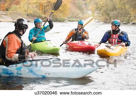Stock Photograph - Male and female kayakers having team talk on River Dee, Llangollen, North Wales. Fotosearch