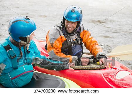 Stock Image - Male and female kayakers talking on River Dee. Fotosearch