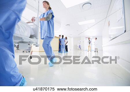 Stock Photography - Male and female medics urgently pushing hospital bed along corridor. Fotosearch