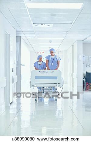 Male and female nurses pushing patient bed on hospital corridor View Large Photo Image Stock Image - Male and female nurses pushing patient bed on hospital corridor. Fotosearch
