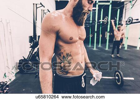 Male cross trainer taking a water break from weightlifting in gym View Large Photo Image Picture - Male cross trainer taking a water break from weightlifting in gym. Fotosearch