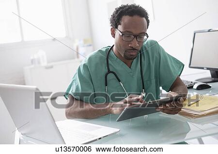Male doctor working with digital tablet at desk View Large Photo Image Stock Photograph - Male doctor working with digital tablet at desk. Fotosearch