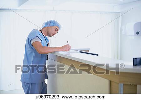 Male doctor writing in medical notes at nurses station in hospital View Large Photo Image Stock Image - Male doctor writing in medical notes at nurses station in hospital. Fotosearch