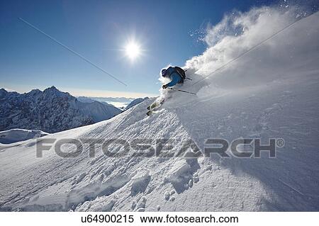 Stock Photography - Male freestyle skier skiing down snow powdered mountainside, Zugspitze, Bayern, Germany. Fotosearch