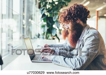 Male hipster twins working on laptop at office desk View Large Photo Image Stock Photo - Male hipster twins working on laptop at office desk. Fotosearch