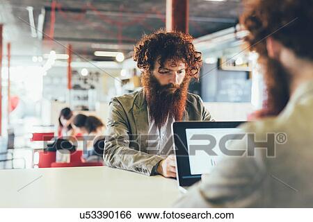 Male hipster twins working on laptop at office desk View Large Photo Image Stock Photograph - Male hipster twins working on laptop at office desk. Fotosearch