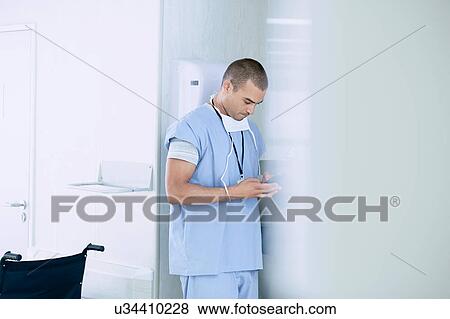 Stock Photo - Male medic using smartphone in hospital ward. Fotosearch