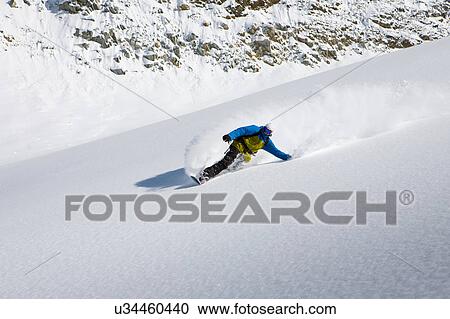 Stock Image - Male snowboarder snowboarding down steep mountain, Trient, Swiss Alps, Switzerland. Fotosearch