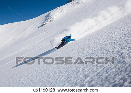 Stock Photo - Male snowboarder speeding down steep mountain, Trient, Swiss Alps, Switzerland. Fotosearch