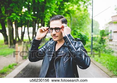 Stock Photograph - Man adjusting spectacles in park. Fotosearch