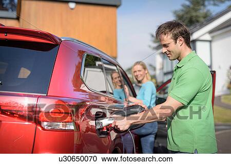 Man and woman charging electric car on street View Large Photo Image Stock Image - Man and woman charging electric car on street. Fotosearch