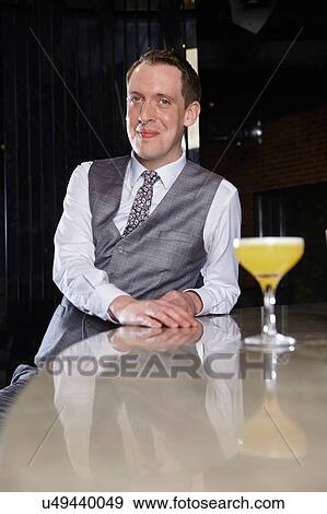 Stock Photo - Man at bar with cocktail looking at camera smiling. Fotosearch