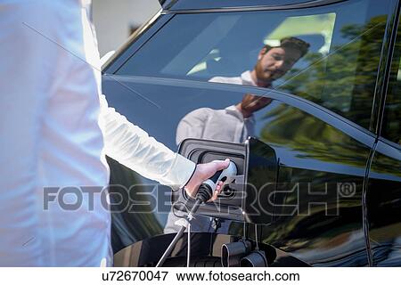 Man charging electric car, close up detail View Large Photo Image Stock Photo - Man charging electric car, close up detail. Fotosearch