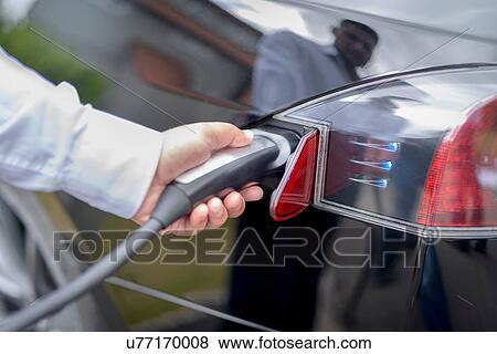 Stock Photo - Man charging electric car, close up detail. Fotosearch