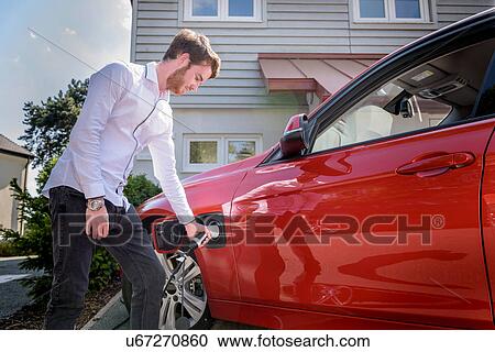Stock Image - Man charging electric car. Fotosearch