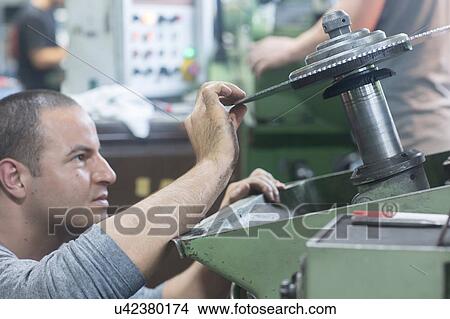 Picture - Man checking rotary blade on grinding machine. Fotosearch