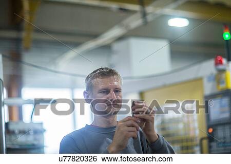 Stock Photograph - Man checking tool in grinding workshop. Fotosearch