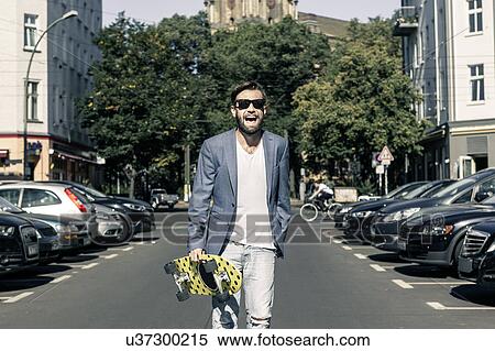 Man holding skateboard in street, Berlin, Germany View Large Photo Image Stock Photography - Man holding skateboard in street, Berlin, Germany. Fotosearch