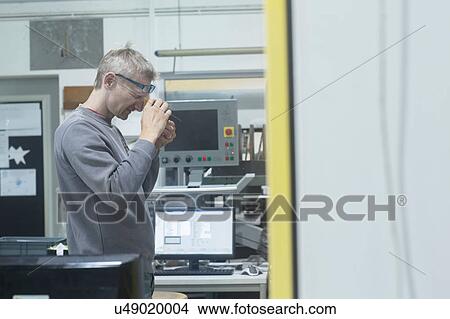 Man looking into magnifying loupe in workshop View Large Photo Image Picture - Man looking into magnifying loupe in workshop. Fotosearch