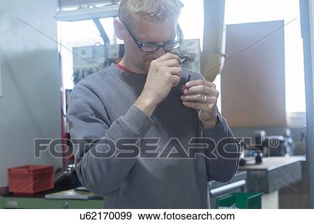 Man looking into magnifying loupe in workshop View Large Photo Image Stock Photo - Man looking into magnifying loupe in workshop. Fotosearch
