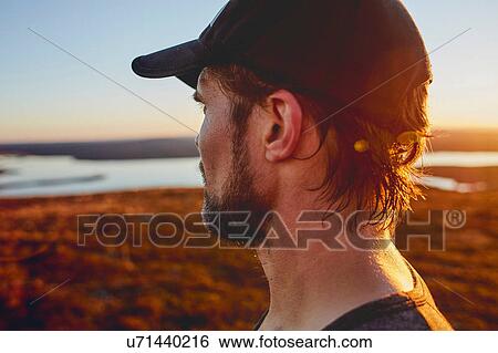 Man looking out to lake on cliff top at sunset, Keimiotunturi, Lapland, Finland View Large Photo Image Stock Photograph - Man looking out to lake on cliff top at sunset, Keimiotunturi, Lapland, Finland. Fotosearch