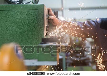 Stock Image - Man monitoring grinding machine in workshop. Fotosearch