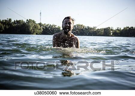 Stock Image - Man, mouth open, splashing in water, Berlin, Germany. Fotosearch