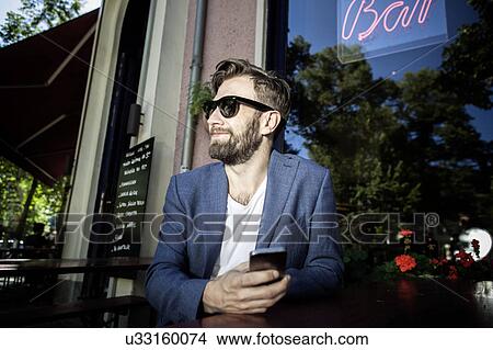 Man outside of bar, holding smartphone smiling, Berlin, Germany View Large Photo Image Picture - Man outside of bar, holding smartphone smiling, Berlin, Germany. Fotosearch