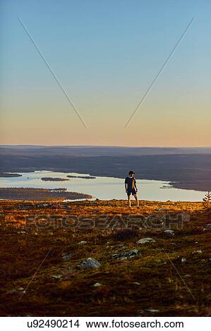 Picture - Man resting after running on cliff top at sunset, Keimiotunturi, Lapland, Finland. Fotosearch