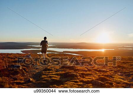 Man running on cliff top at sunset, Keimiotunturi, Lapland, Finland View Large Photo Image Picture - Man running on cliff top at sunset, Keimiotunturi, Lapland, Finland. Fotosearch