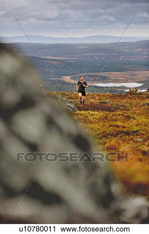 Stock Image - Man running on rocky cliff top, Keimiotunturi, Lapland, Finland. Fotosearch