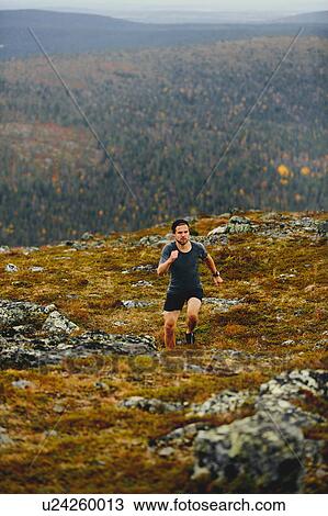 Stock Image - Man running on rocky cliff top, Keimiotunturi, Lapland, Finland. Fotosearch