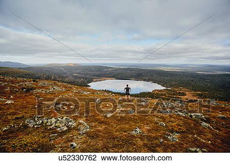Stock Image - Man running on rocky cliff top, Keimiotunturi, Lapland, Finland. Fotosearch