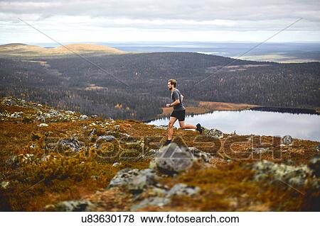 Stock Photo - Man running on rocky cliff top, Keimiotunturi, Lapland, Finland. Fotosearch