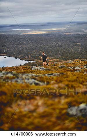 Stock Photograph - Man running on rocky cliff top, Keimiotunturi, Lapland, Finland. Fotosearch