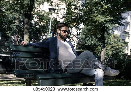 Stock Image - Man sitting on park bench, Berlin, Germany. Fotosearch