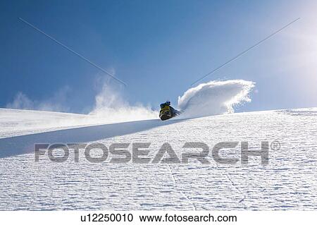 Stock Image - Man snowboarding down steep mountain, Trient, Swiss Alps, Switzerland. Fotosearch