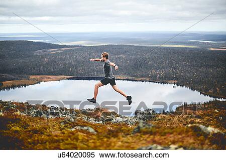 Stock Photography - Man sprinting on rocky cliff top, Keimiotunturi, Lapland, Finland. Fotosearch
