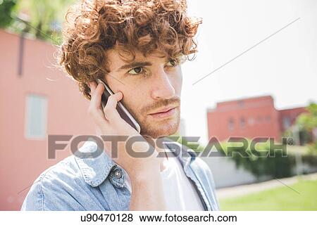 Stock Photo - Man using cellular phone outdoors. Fotosearch
