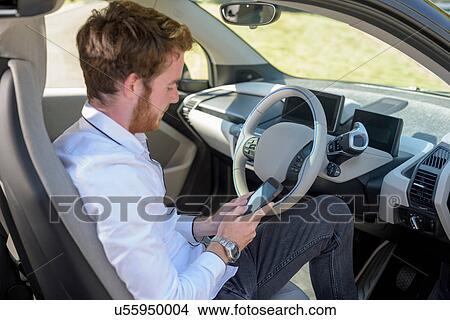 Man using mobile phone in electric car View Large Photo Image Picture - Man using mobile phone in electric car. Fotosearch