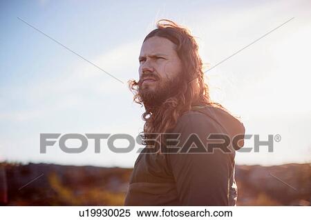 Stock Photography - Man with long hair frowning in hot sun. Fotosearch