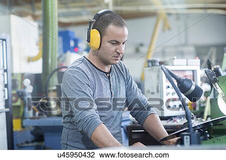 Stock Image - Man working in grinding workshop. Fotosearch