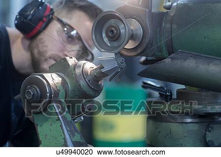 Stock Image - Man working in grinding workshop. Fotosearch